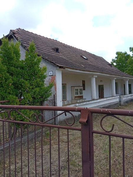 A family house in Ňárad with a white facade and a sloped roof with a wooden fence.
