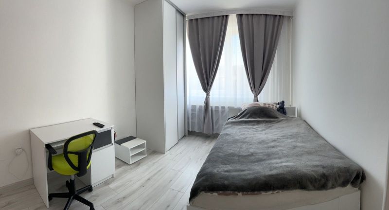 A minimalist bedroom in a family house with a desk and a wooden decor floor.