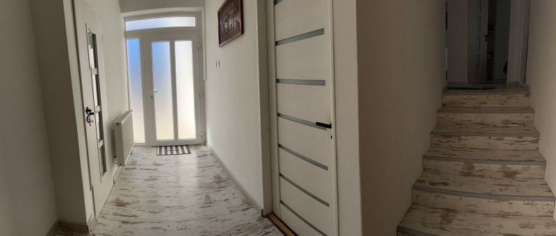 A hallway of a family house with a wooden decor floor and light-colored doors.