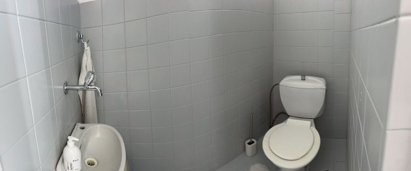 Bathroom with white tiles, a sink, and a toilet in a family house.