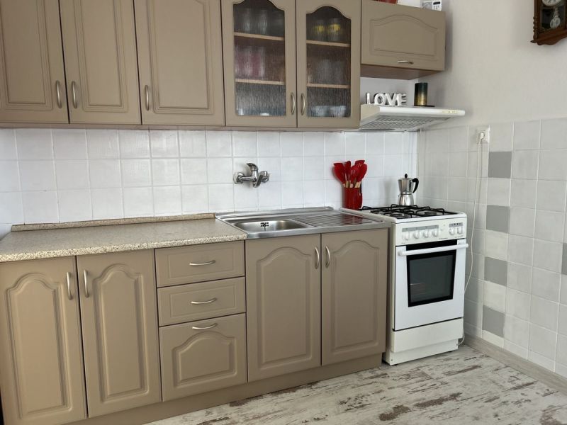 A kitchen in a family house with beige cabinets, a white stove, and decorative accessories.