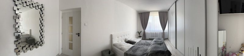 A bedroom in a family house with white furniture, gray curtains, and a decorative mirror.