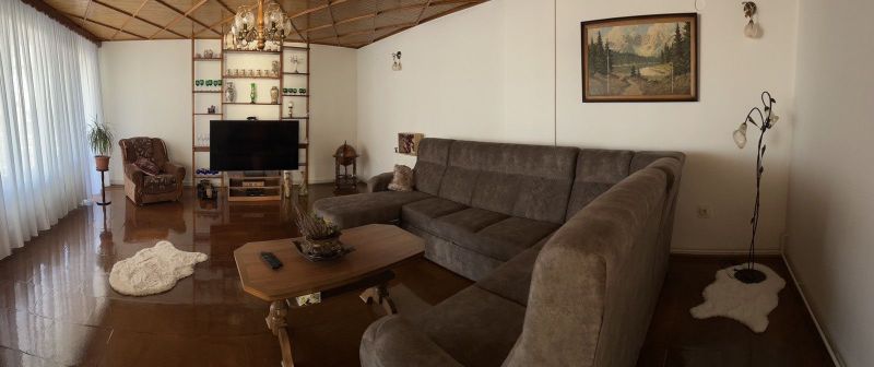 Living room in a family house with a sofa set and a television, floor with wooden decor.