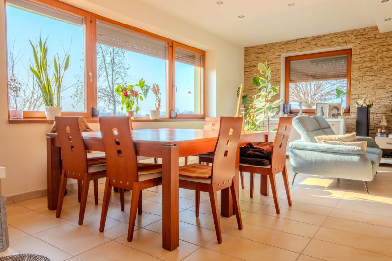Dining room in a family house with a spacious table, wooden chairs, and plant decorations.