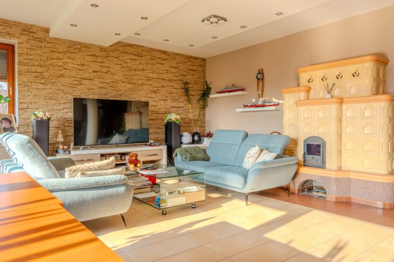 Living room in a family house with upholstered furniture, a television, and tiled stoves.