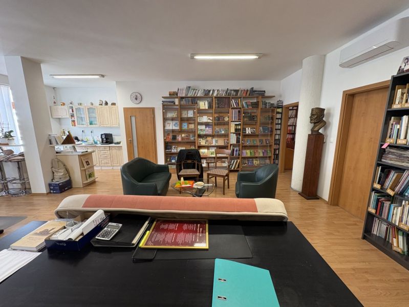 Living room with a library, kitchen, and wooden decor flooring in a 3-room apartment.