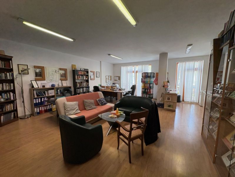 Living room with a sofa, bookshelf, desk, and wooden decor flooring.