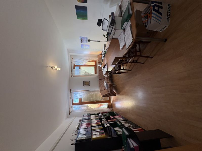 A study with a wooden decor floor in a 3-room apartment, full of documents and furniture.