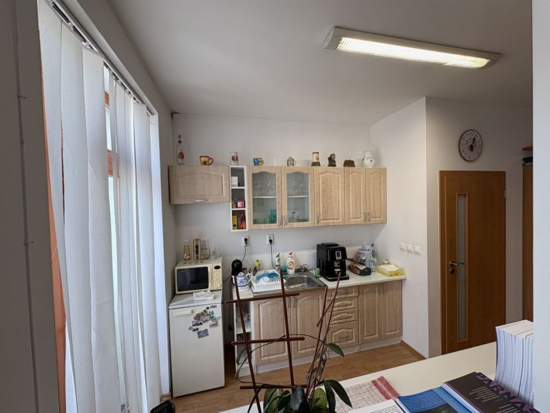 A kitchen in a 3-room apartment with a wooden decor floor and kitchen cabinets.