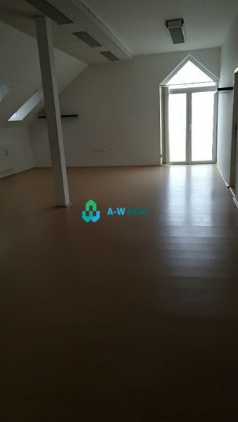 Empty offices with wood-patterned flooring and a large window.