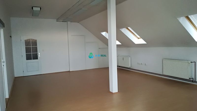 Attic office with white walls and a wooden decor floor.