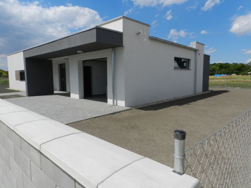 A family house in Dolný Bar with a fence and a paved area under the blue sky.