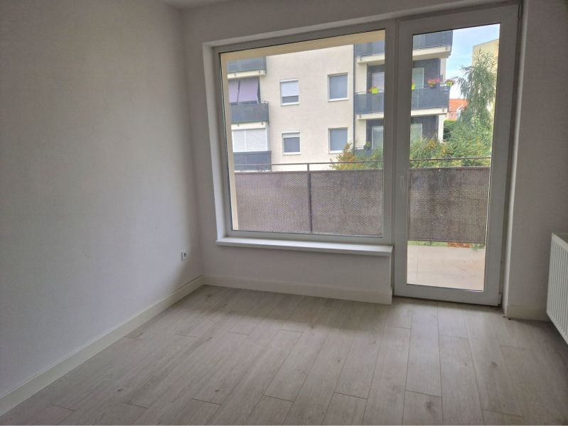 A room in a 3-room apartment with a floor featuring a wooden decor and balcony doors.
