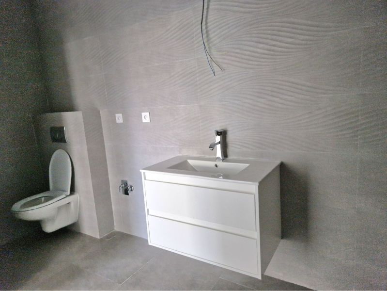 A bathroom in a 3-room apartment with a white sink and gray tiles.