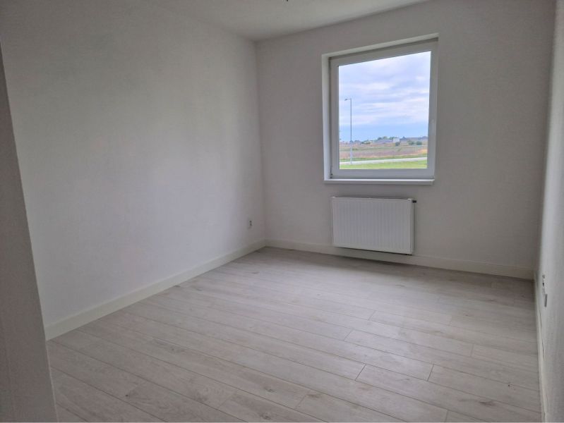 A room with white walls and a wooden decor floor in a 3-room apartment.