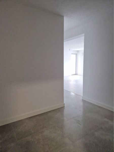 A bright hallway of a 3-room apartment with tiles leads to a sunlit room.