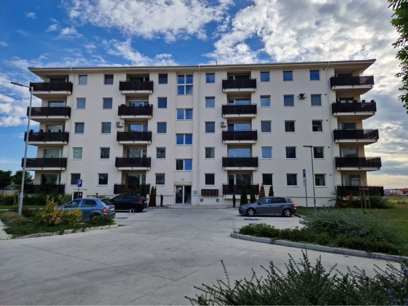A four-story building with a light facade and parking in Dunajská Streda on an unspecified street.