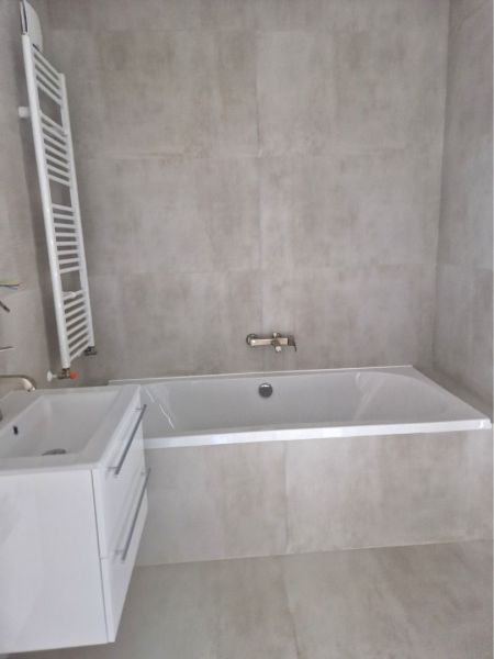 Bathroom in a 3-room apartment with a bathtub and a sink, light tiles on the walls.
