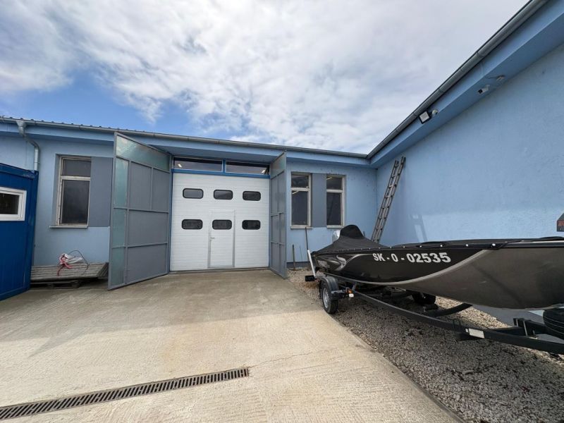Warehouse and hall building in Orechová Potôň with a parked boat on a concrete surface.