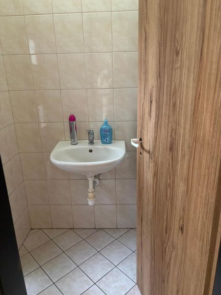 Small bathroom with a sink, tiles, and a door with a wooden decor.