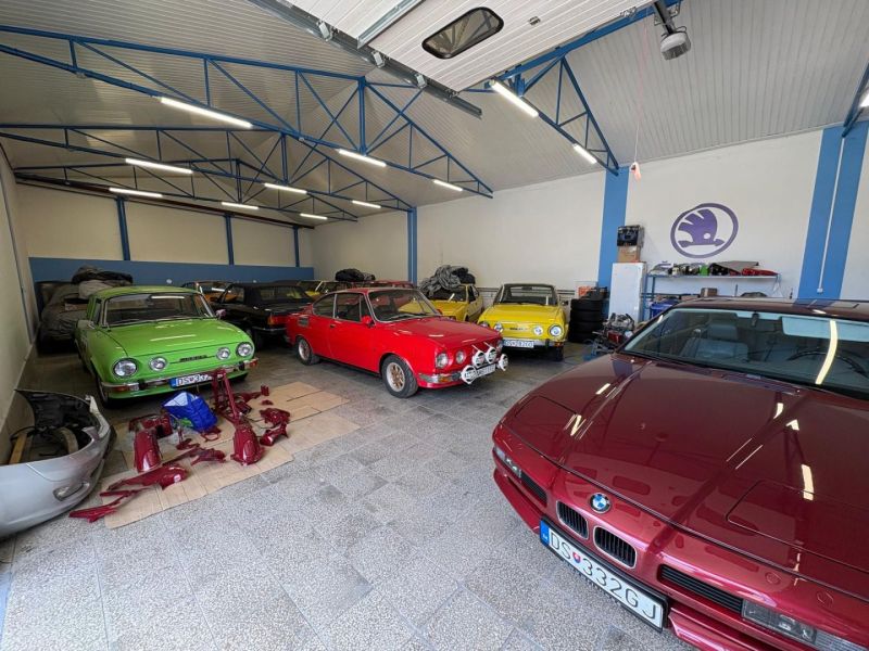 Warehouses and halls with vintage cars and auto parts on a floor with wooden decor.