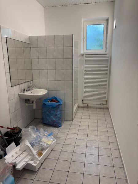 Bathroom with tiles, sink, window, and drying rack in the space of warehouses and halls.