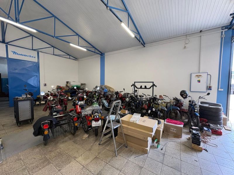 The interior of a workshop with motorcycles and parts on the floor. Warehouses and halls.