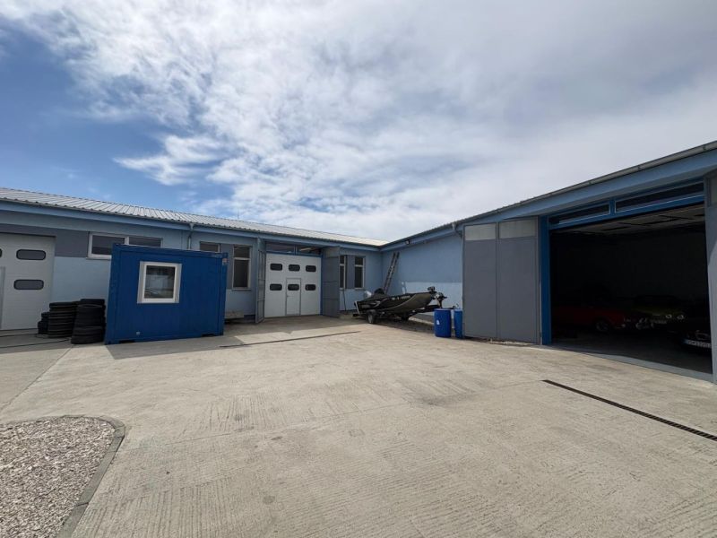 Warehouses and halls in Orechová Potôň with a parked trailer and a blue container.