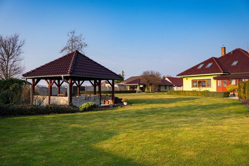A garden with a gazebo and a family house in Dolný Bar, surrounded by a lawn.