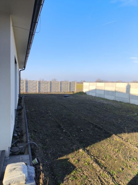 A family house in Michal na Ostrove with a grassy garden and a concrete fence.