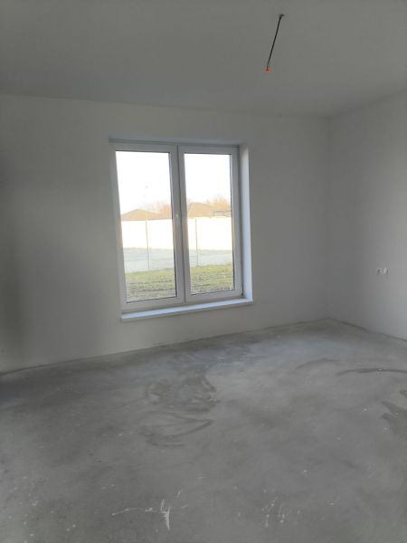 A room in a family house with a large window and a concrete floor.