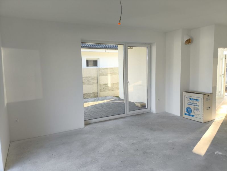 A white space in a family house with a view of the garden through glass doors.