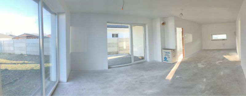 Interior in a family house with large windows and concrete floor.