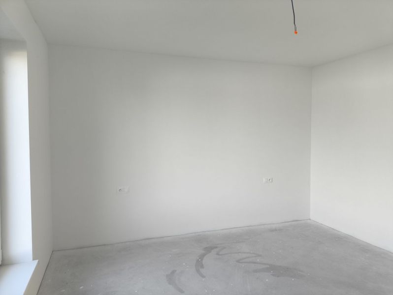 Empty room with white walls and a concrete floor in a family house.