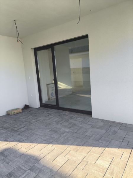 The terrace of a family house in Michal na Ostrove with tiled flooring and glass doors.