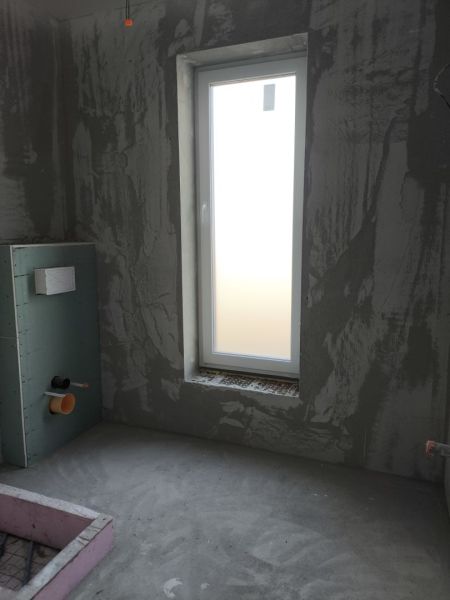 Construction of a bathroom in a family house with a window and a prepared installation system.