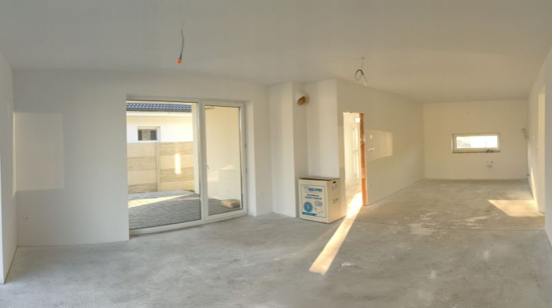 A spacious interior of a family house with large sliding doors and white walls.