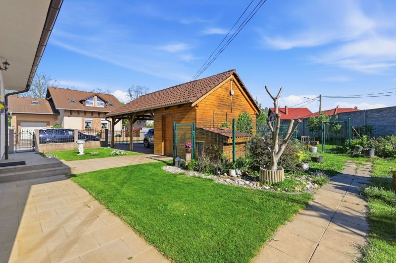 A family house in Kostolné Kračany with a lawn, a wooden extension, and a carport.