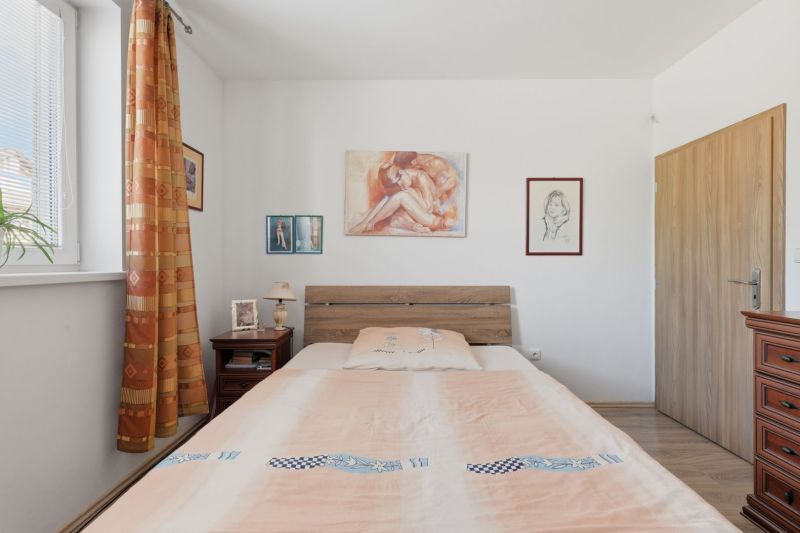 Bedroom in a family house with paintings, a bed, and a nightstand, floor with wooden decor.