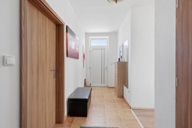 A hallway in a family house with tiles, wooden doors, and decorations on the walls.