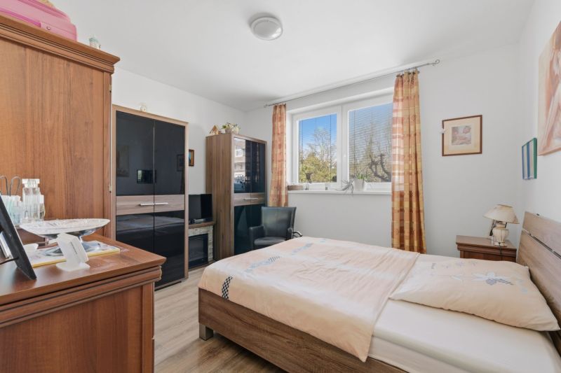 A bedroom in a family house with dark wood furniture and a wooden-patterned floor.