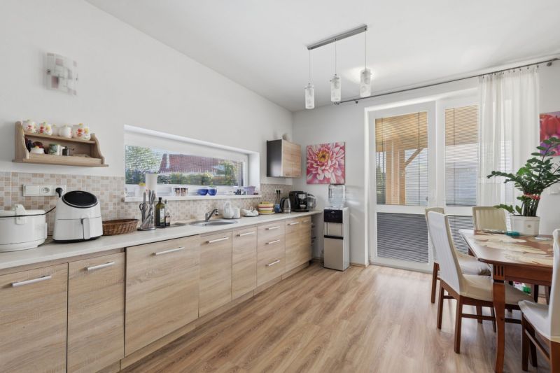 A kitchen in a family house with a wood-patterned floor, a dining table, and decorations.