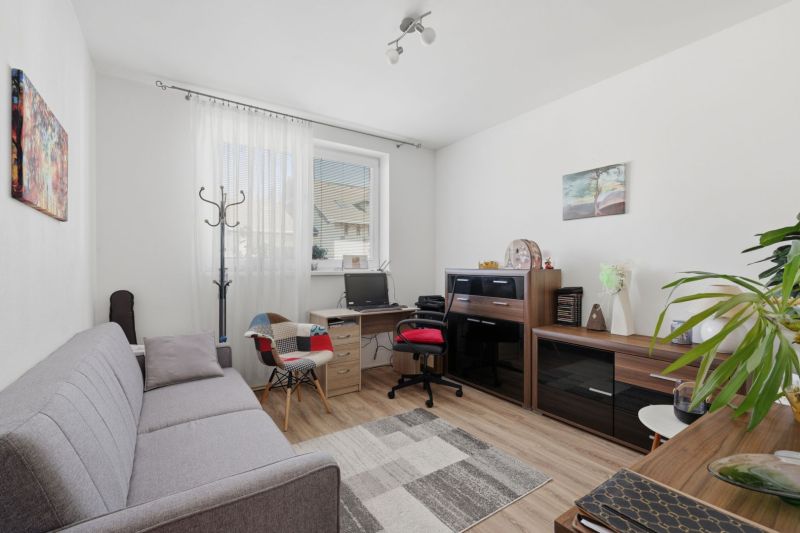 Living room with a computer desk, sofa, and wooden decor flooring in a family house.