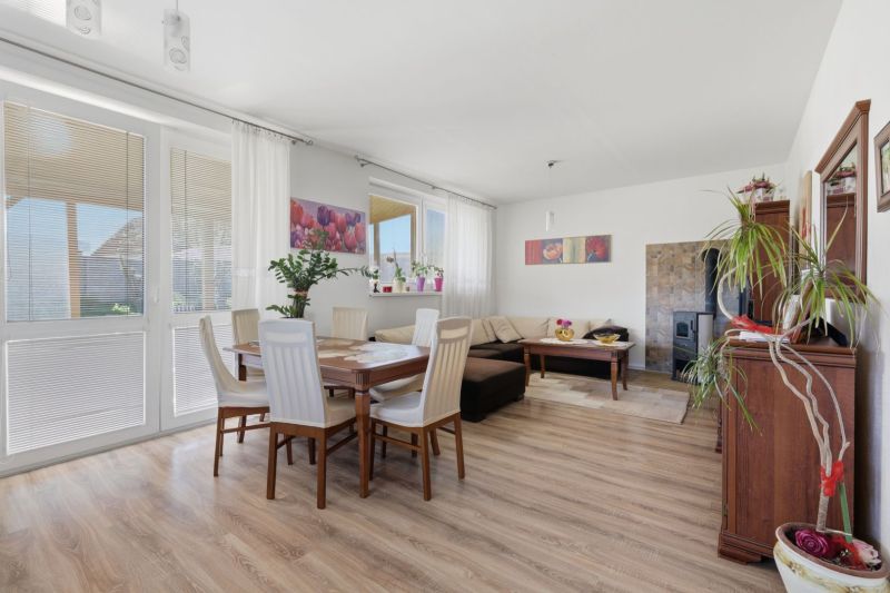 Living room in a family house with wood-decor flooring and a dining area.