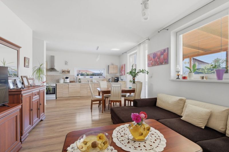 Spacious living room with kitchen in a family house, wooden decor flooring, light colors.