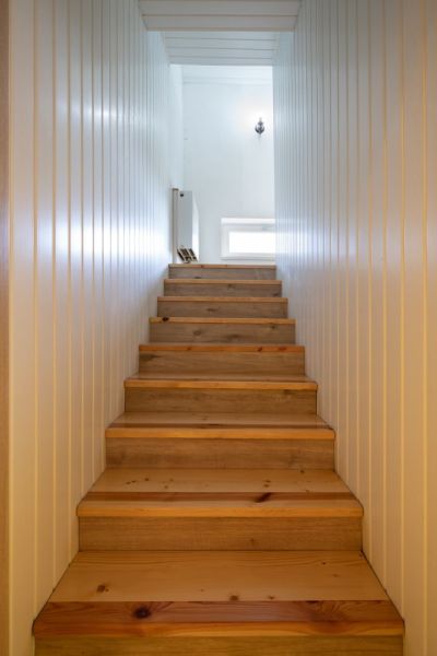 A staircase with a wooden decor and walls in white shades in a family house.