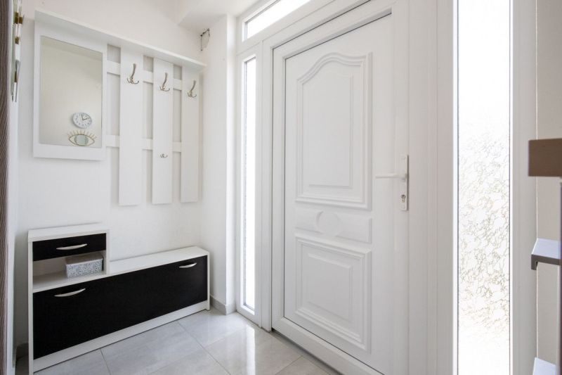 White hallway in a family house with a coat rack, storage space, and a mirror.