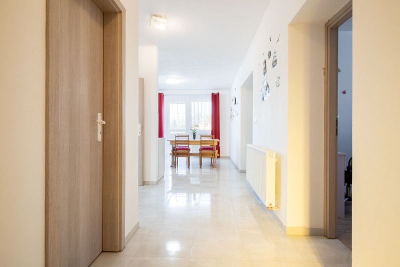 The interior of a family house with a transition to the dining room, where there are chairs and a table by the window.