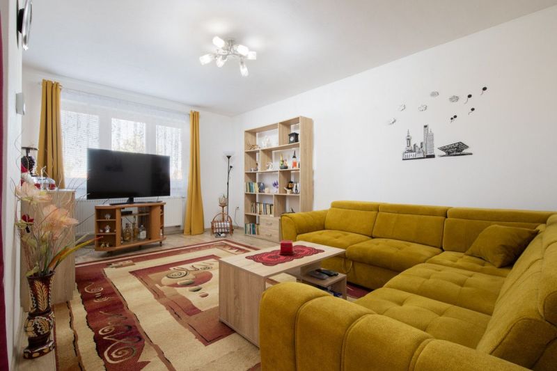 A living room in a family house with a comfortable yellow sofa and a television.