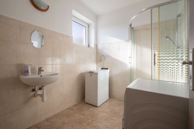 A bathroom in a family house with a shower, a sink, and a washing machine.